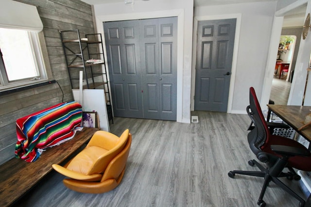 home office with wooden walls and light hardwood / wood-style floors