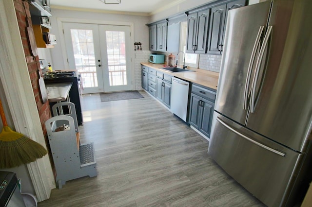 kitchen featuring french doors, light countertops, appliances with stainless steel finishes, a sink, and wood finished floors