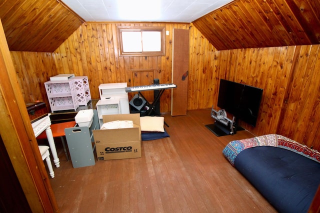 interior space featuring wooden walls, vaulted ceiling, and hardwood / wood-style floors