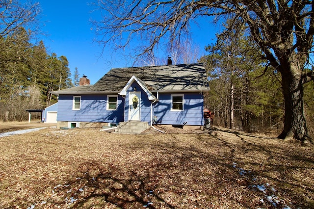 view of front facade featuring a garage, entry steps, driveway, and a chimney