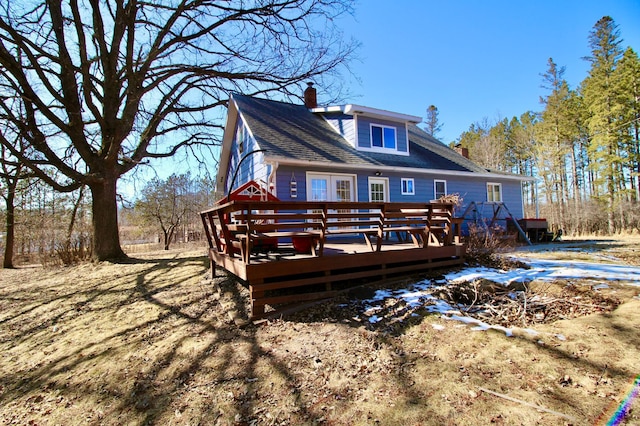 back of house with roof with shingles, a chimney, and a deck