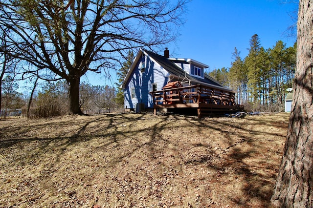 view of side of home with a deck and a chimney