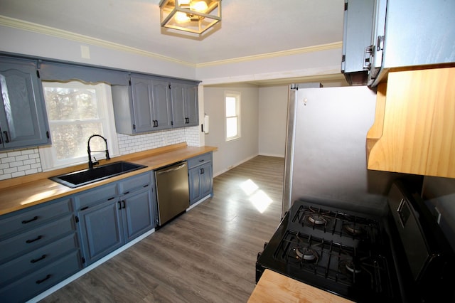 kitchen featuring a sink, dark wood-style flooring, crown molding, stainless steel appliances, and blue cabinets