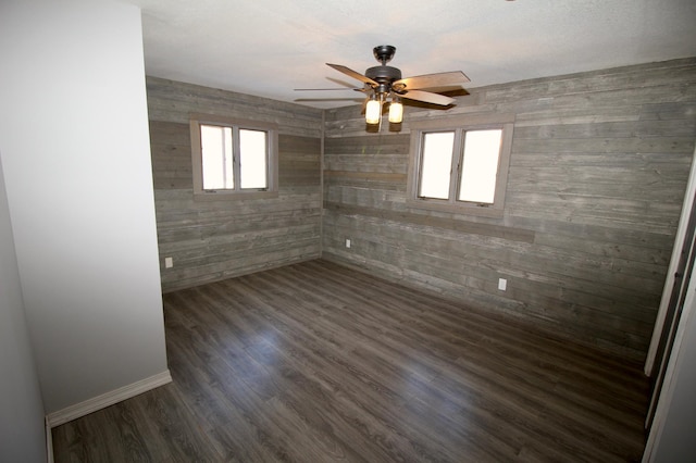 spare room featuring dark wood-style flooring, a ceiling fan, and plenty of natural light