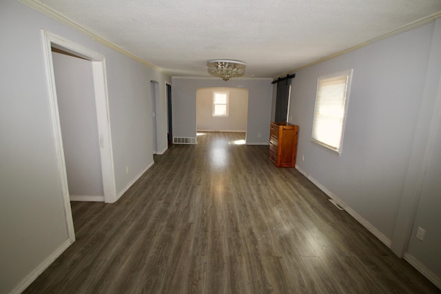 interior space with dark wood-type flooring, baseboards, a barn door, and crown molding