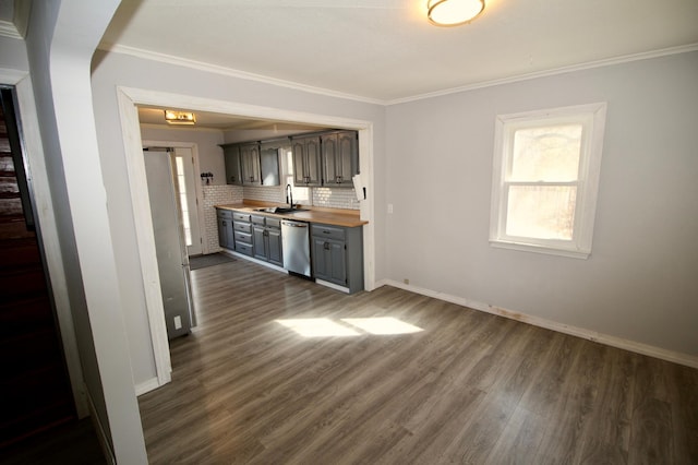 kitchen featuring a sink, ornamental molding, stainless steel appliances, butcher block countertops, and decorative backsplash
