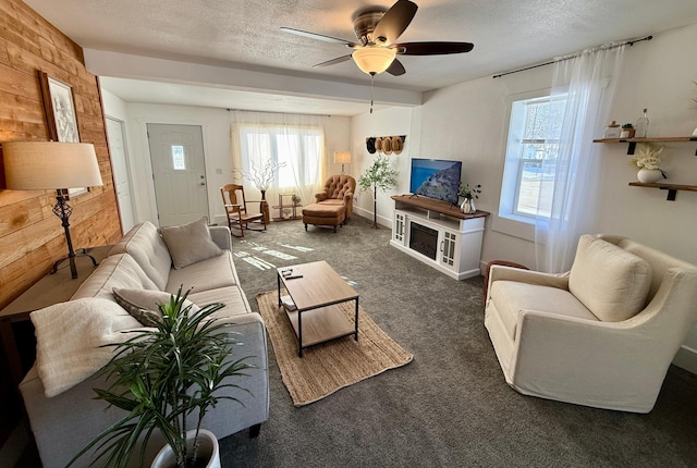 living room featuring dark carpet, ceiling fan, a textured ceiling, and wooden walls