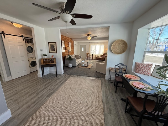 sitting room featuring dark hardwood / wood-style flooring, a barn door, stacked washer / drying machine, and a textured ceiling