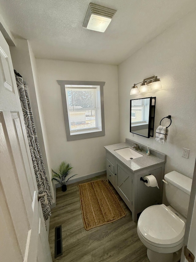 bathroom with a textured ceiling, toilet, vanity, and hardwood / wood-style floors