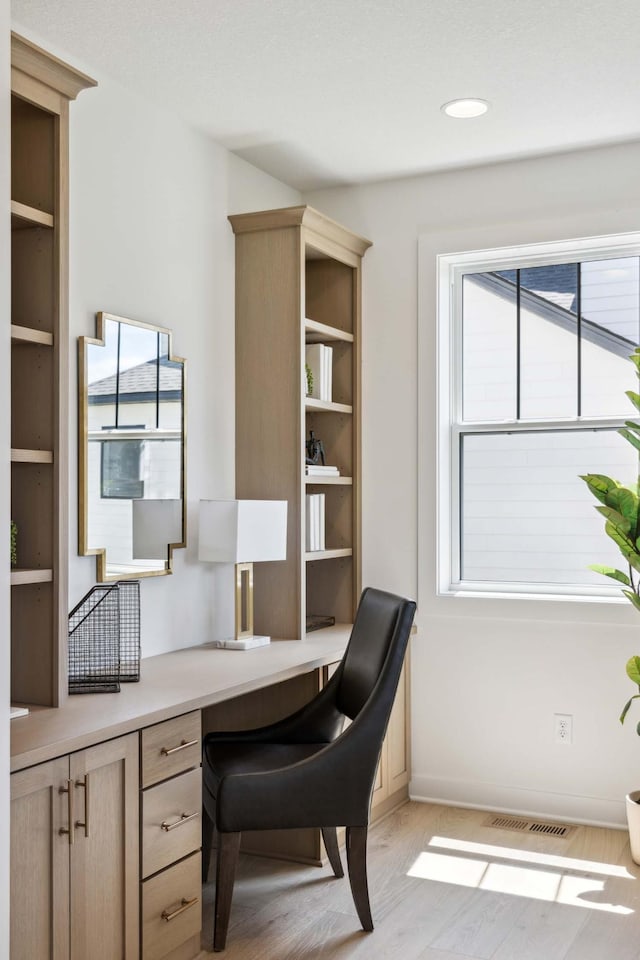 office with built in desk and light wood-type flooring