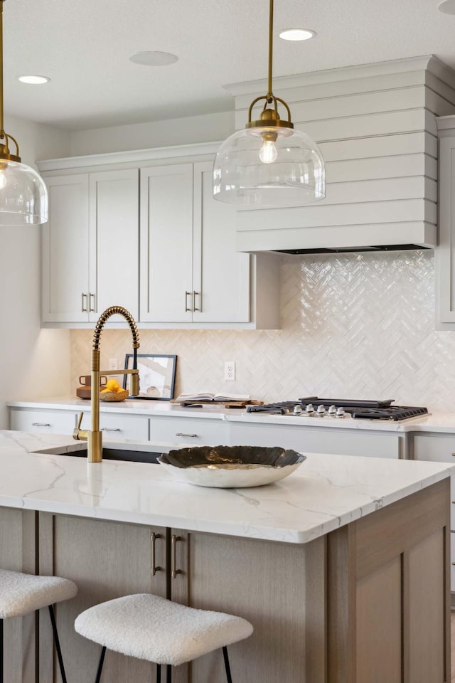 kitchen with white cabinets, light stone countertops, backsplash, and decorative light fixtures