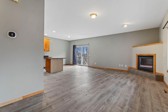 unfurnished living room featuring a tiled fireplace and light hardwood / wood-style flooring