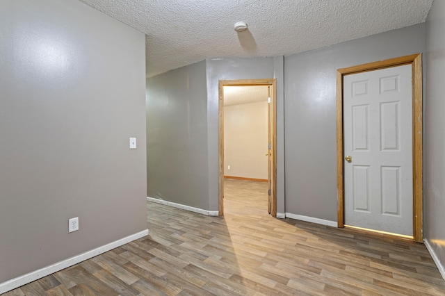 unfurnished room featuring light wood-type flooring and a textured ceiling