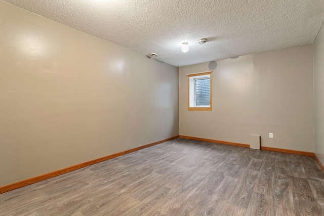 unfurnished room with a textured ceiling and hardwood / wood-style flooring