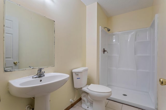 bathroom with a shower, sink, tile patterned flooring, and toilet