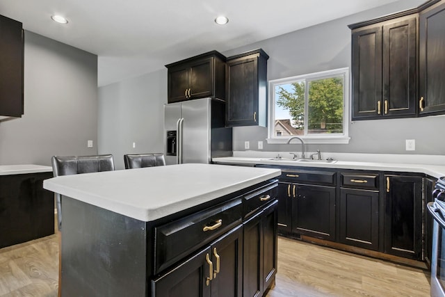 kitchen with stove, stainless steel fridge with ice dispenser, a center island, light hardwood / wood-style flooring, and sink