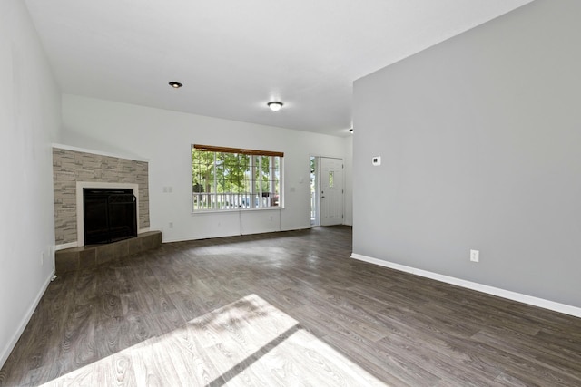 unfurnished living room with a tile fireplace and dark wood-type flooring