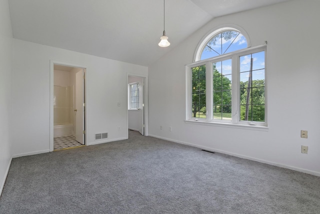 unfurnished bedroom with ensuite bath, vaulted ceiling, carpet floors, and multiple windows