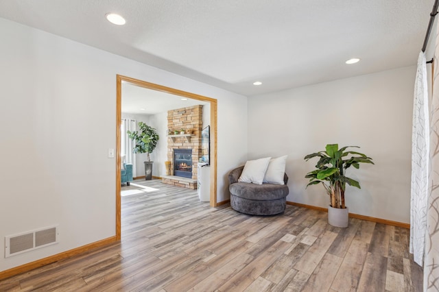 sitting room featuring visible vents, baseboards, wood finished floors, and a fireplace