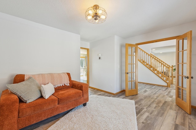 living area with french doors, baseboards, wood finished floors, and stairs