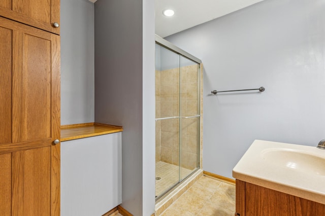 full bathroom featuring tile patterned flooring, a stall shower, vanity, and baseboards