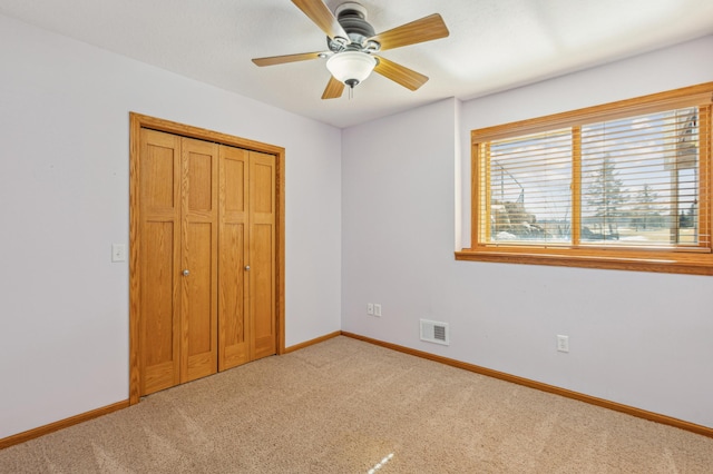 unfurnished bedroom with light colored carpet, visible vents, a closet, and baseboards