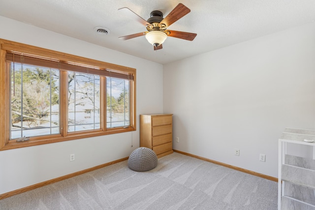 interior space with light carpet, visible vents, ceiling fan, and baseboards