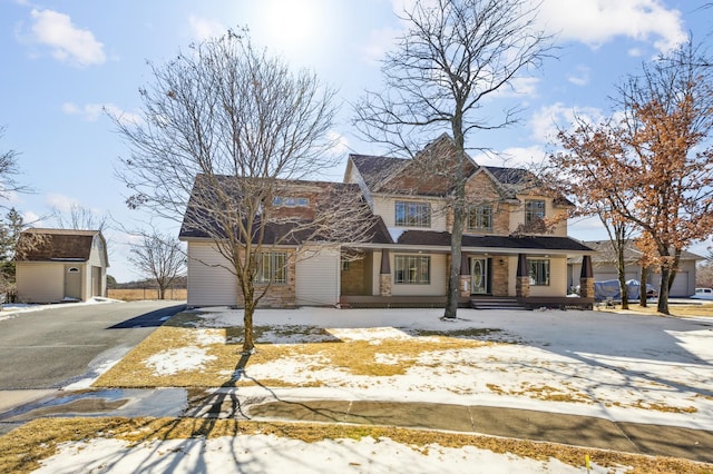 view of front of house featuring an outbuilding, a shed, and aphalt driveway