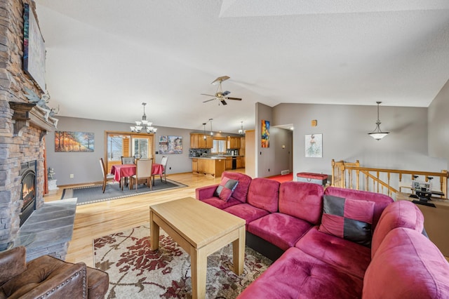 living area featuring baseboards, lofted ceiling, wood finished floors, a textured ceiling, and a stone fireplace