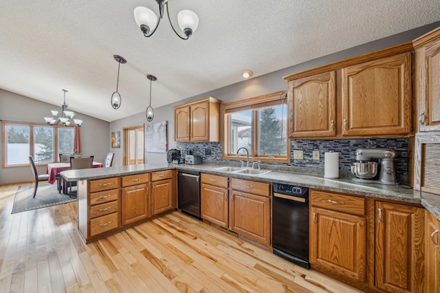 kitchen with brown cabinetry, a peninsula, a sink, pendant lighting, and a notable chandelier