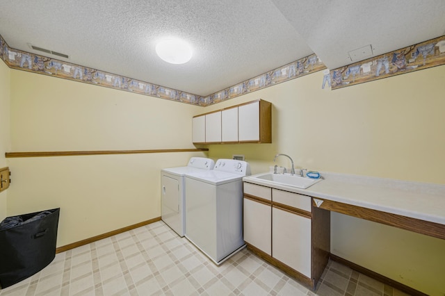 washroom with cabinet space, visible vents, washing machine and clothes dryer, a textured ceiling, and a sink