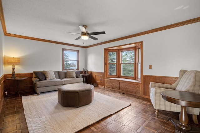 living room with crown molding, ceiling fan, a textured ceiling, and wood walls