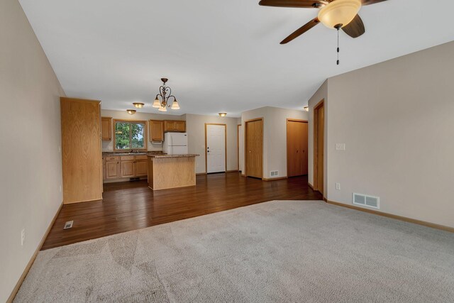 615 Cottonwood Ave, Litchfield, MN 55355 - unfurnished living room featuring dark carpet, a ceiling fan, baseboards, and a chandelier