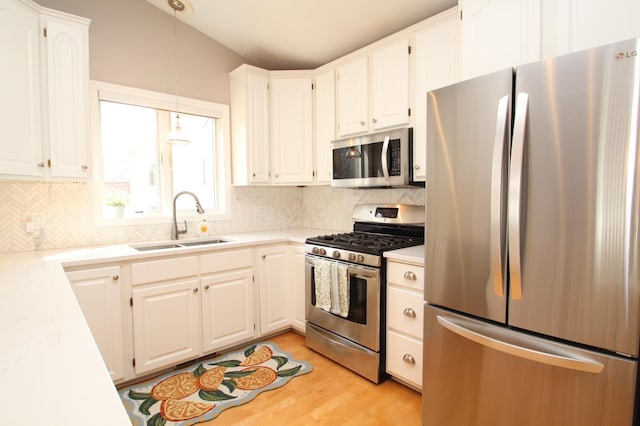 kitchen with white cabinets, a sink, light countertops, stainless steel appliances, and backsplash