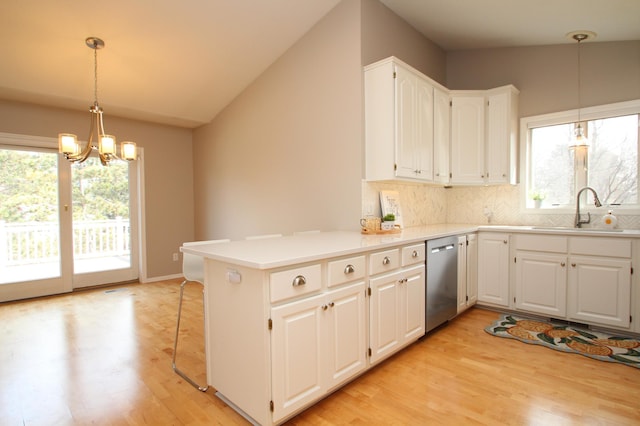 kitchen with a sink, a chandelier, light wood-style floors, backsplash, and stainless steel dishwasher