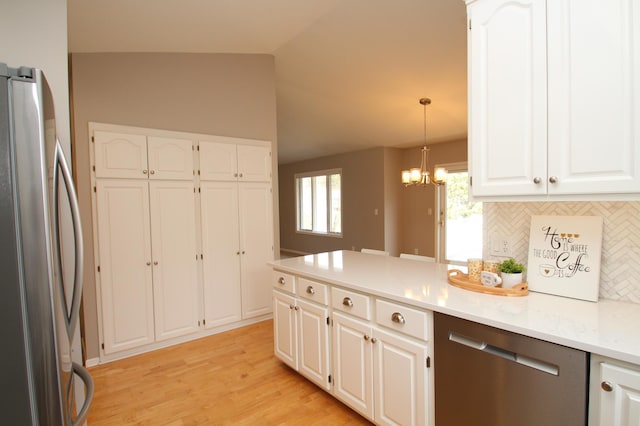 kitchen featuring tasteful backsplash, appliances with stainless steel finishes, an inviting chandelier, and white cabinetry