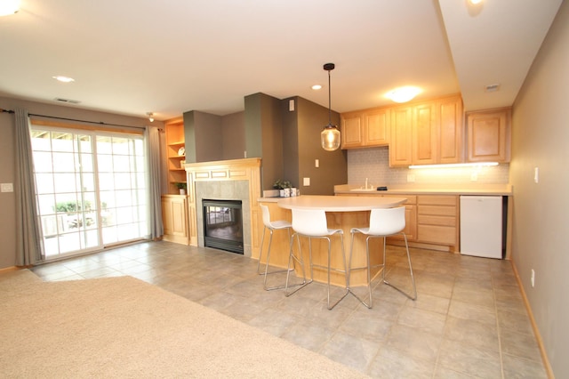 kitchen featuring light countertops, dishwasher, light brown cabinetry, and baseboards