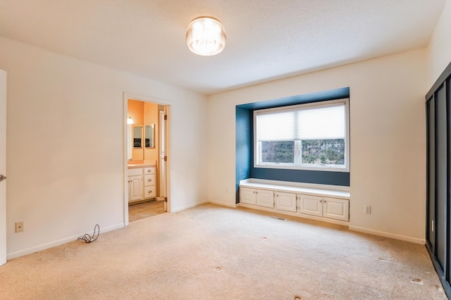 unfurnished bedroom with light carpet, visible vents, baseboards, and connected bathroom