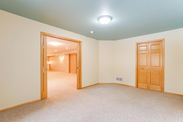 carpeted spare room with visible vents and baseboards
