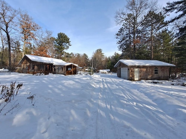 snowy yard with a garage and an outdoor structure