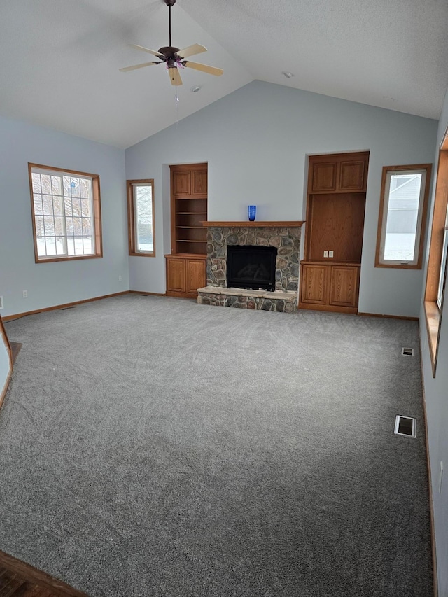 unfurnished living room with ceiling fan, lofted ceiling, a fireplace, and dark colored carpet