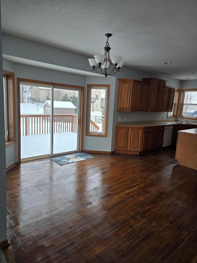 kitchen with dark wood-type flooring, dishwasher, hanging light fixtures, a notable chandelier, and a textured ceiling