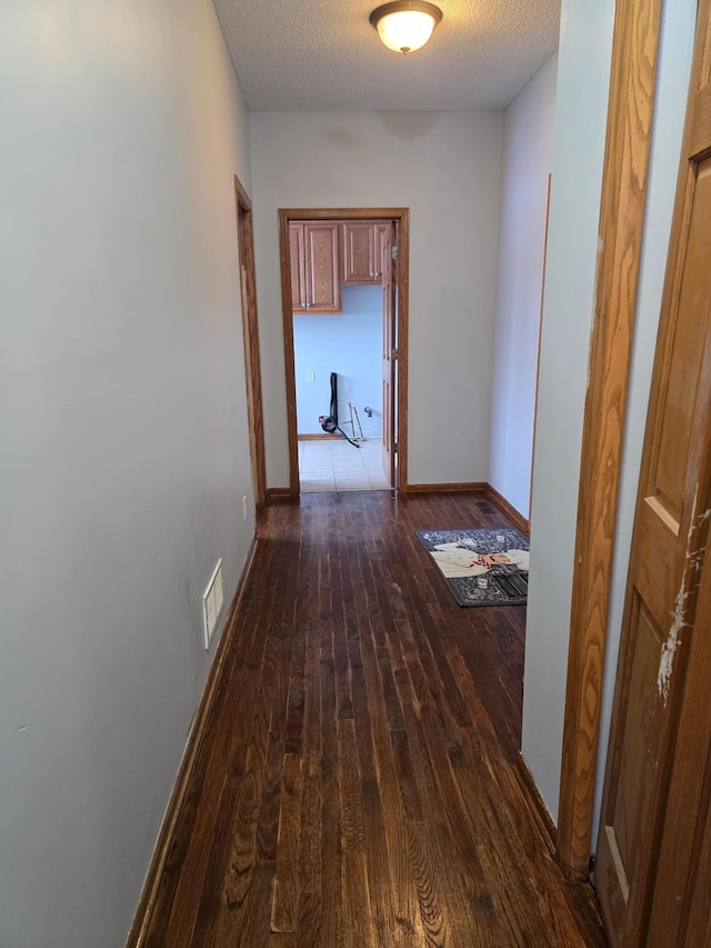 hall featuring dark wood-type flooring and a textured ceiling