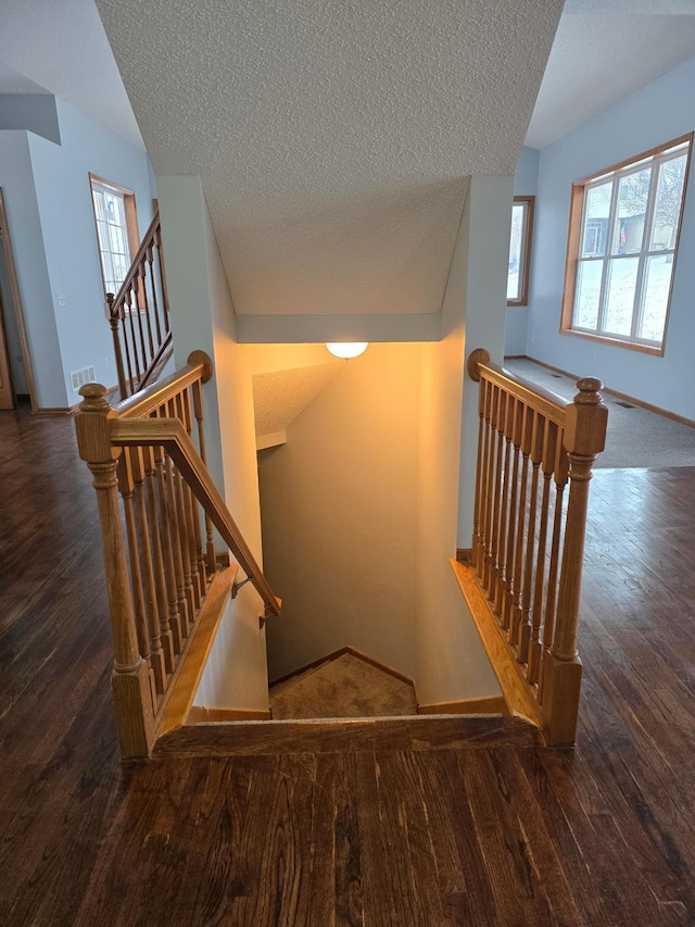 stairs featuring hardwood / wood-style floors and a textured ceiling