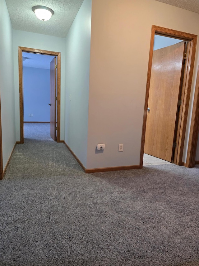 hall featuring carpet floors and a textured ceiling