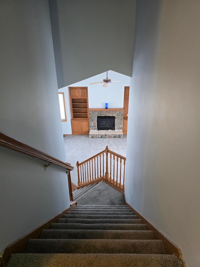 stairway with a high ceiling, carpet floors, a fireplace, and ceiling fan