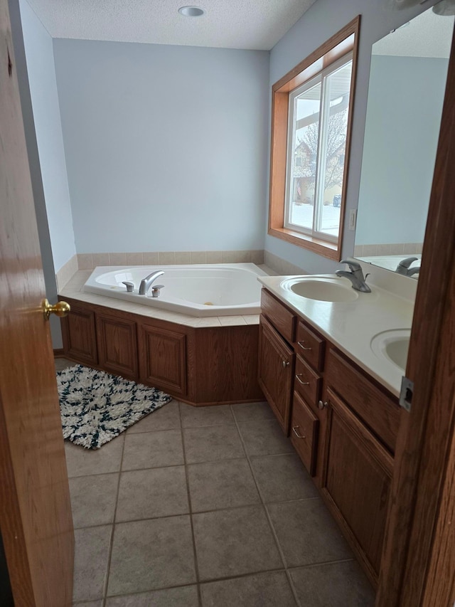 bathroom with a tub to relax in, tile patterned floors, a textured ceiling, and vanity