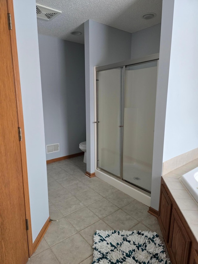 bathroom with tile patterned floors, toilet, a textured ceiling, and separate shower and tub