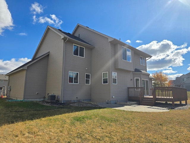 rear view of house with a wooden deck, cooling unit, and a lawn