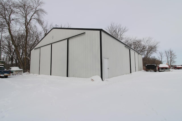 snow covered structure with an outbuilding and a pole building